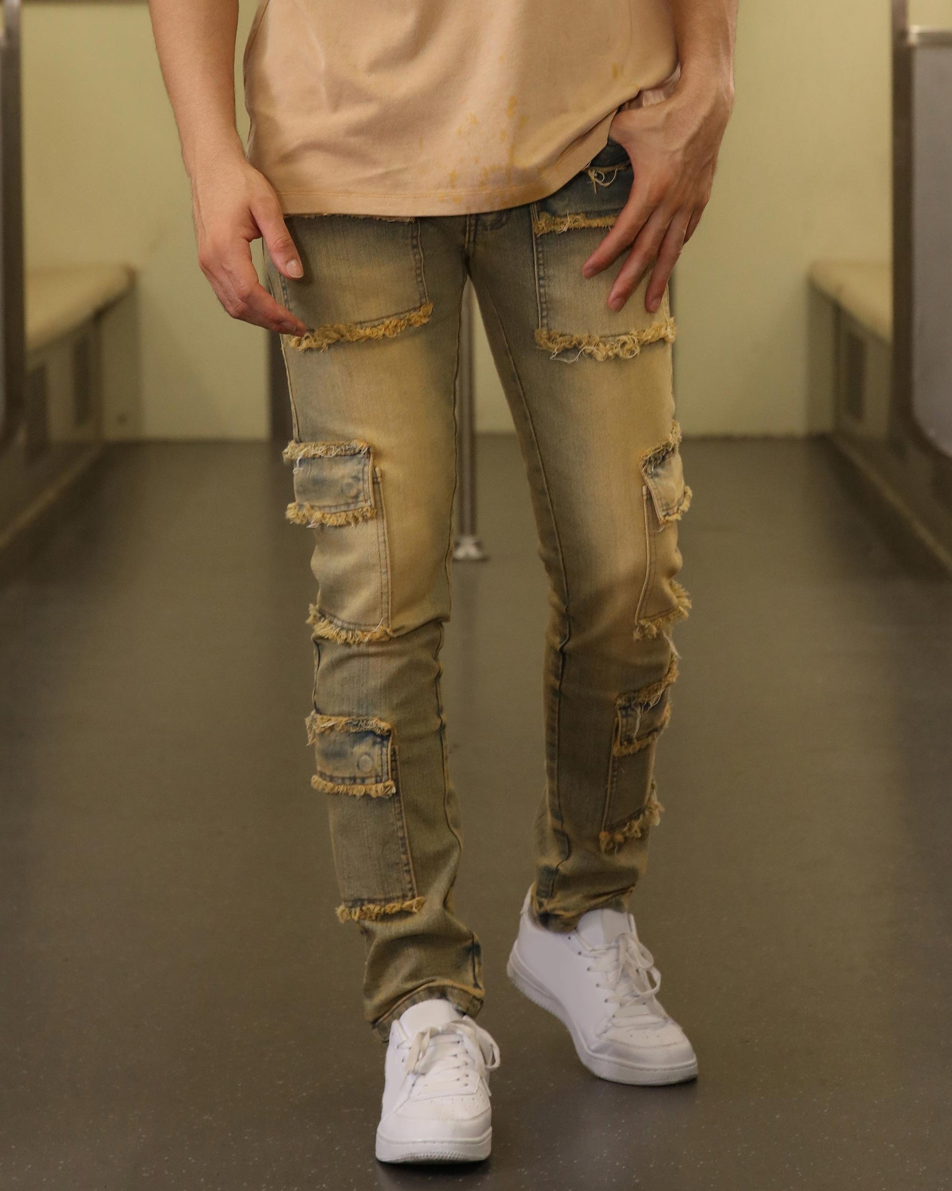 Logeqi raw edge brown jeans with distressed patches and frayed detailing worn with white sneakers