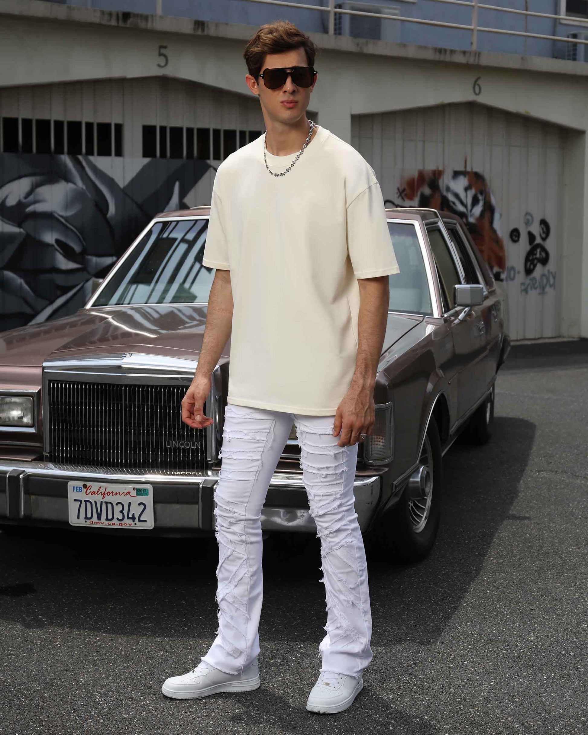 Logeqi retro white flared jeans featured on a model standing next to a vintage car