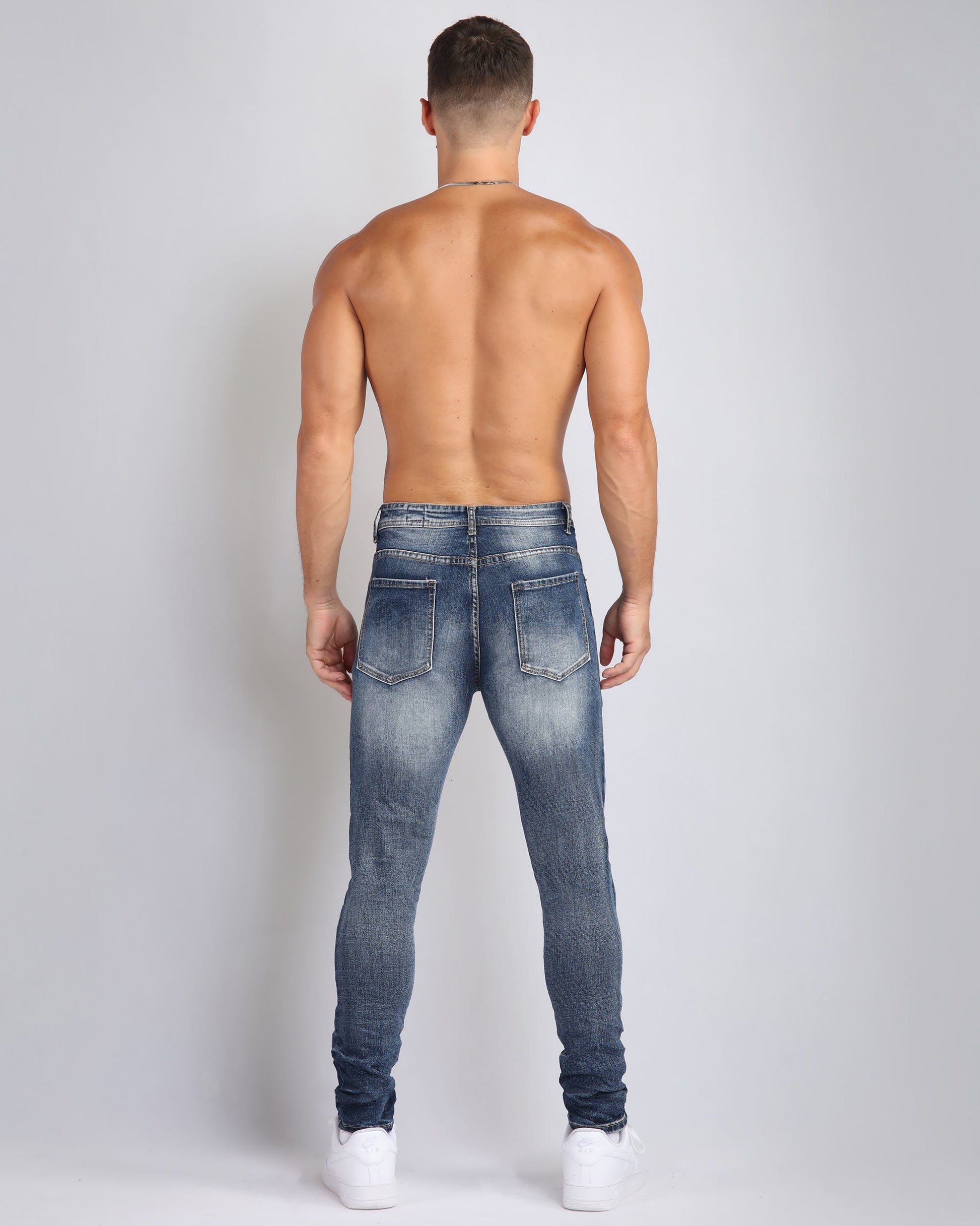 Logeqi ripped blue jeans with flower patch viewed from the back, showcasing a stylish and modern fit