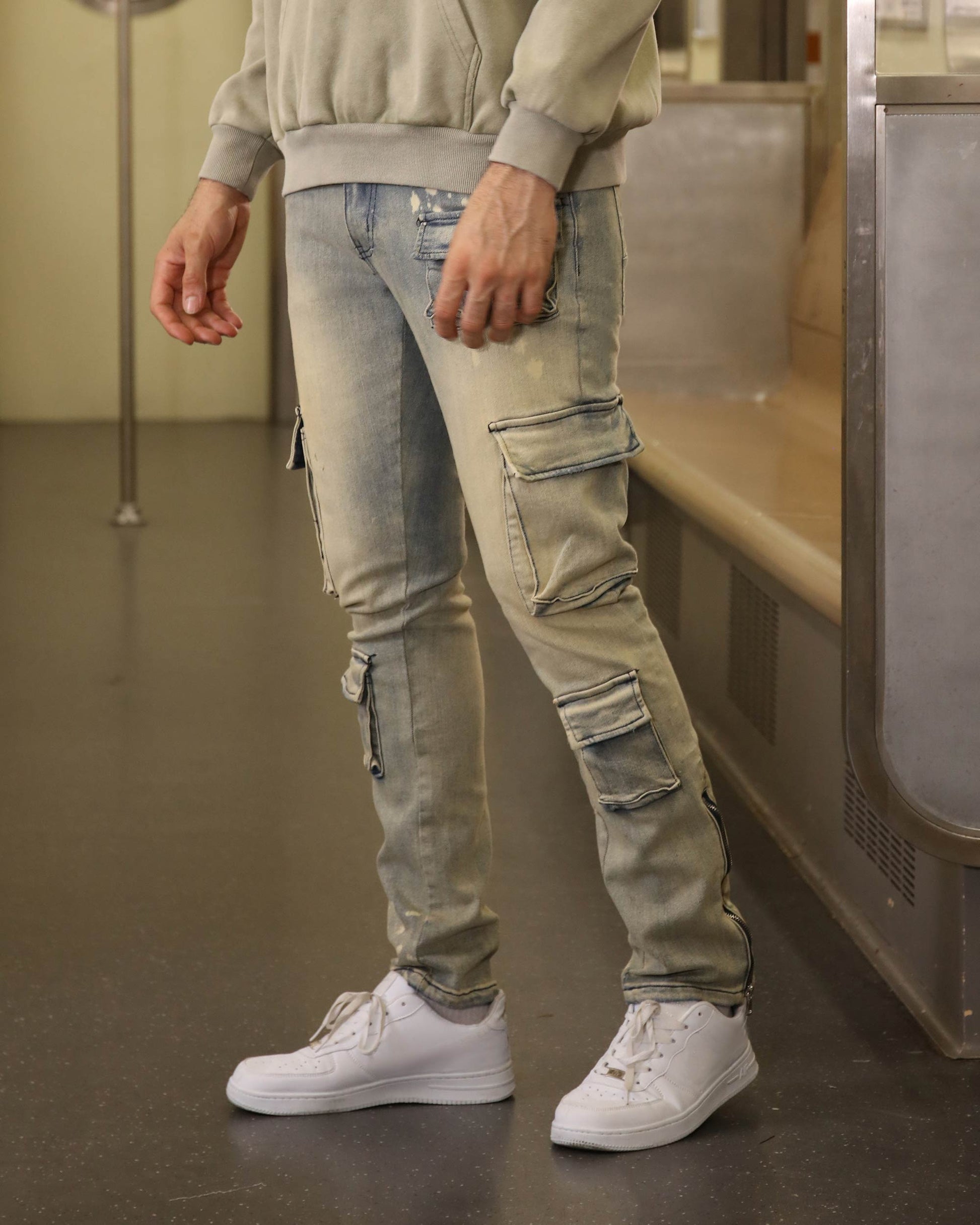 Logeqi spray painted blue cargo jeans with multiple side pockets worn with white sneakers