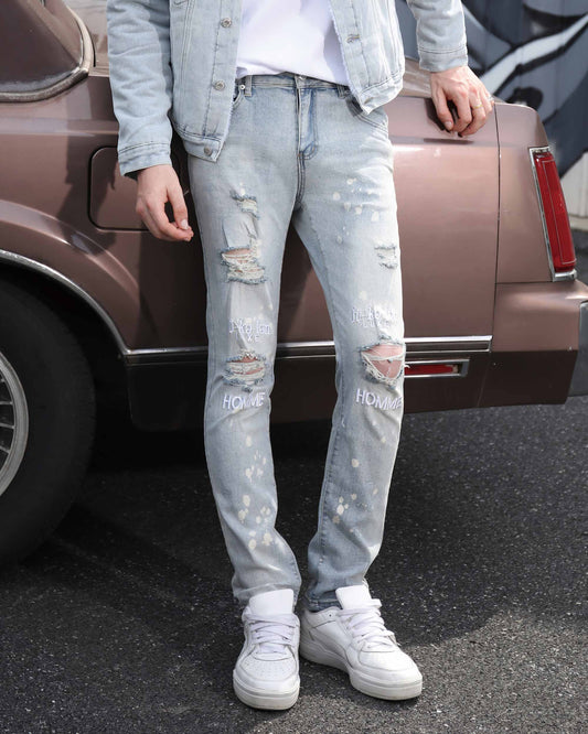 Logeqi spray painted light blue ripped jeans with distressed details worn with white sneakers