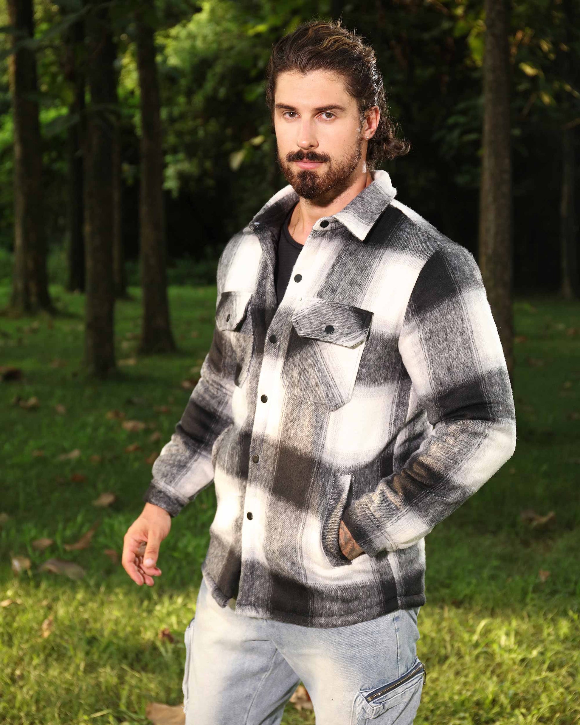 Man wearing a black and white spring plaid jacket by Logeqi outdoors in a forest setting