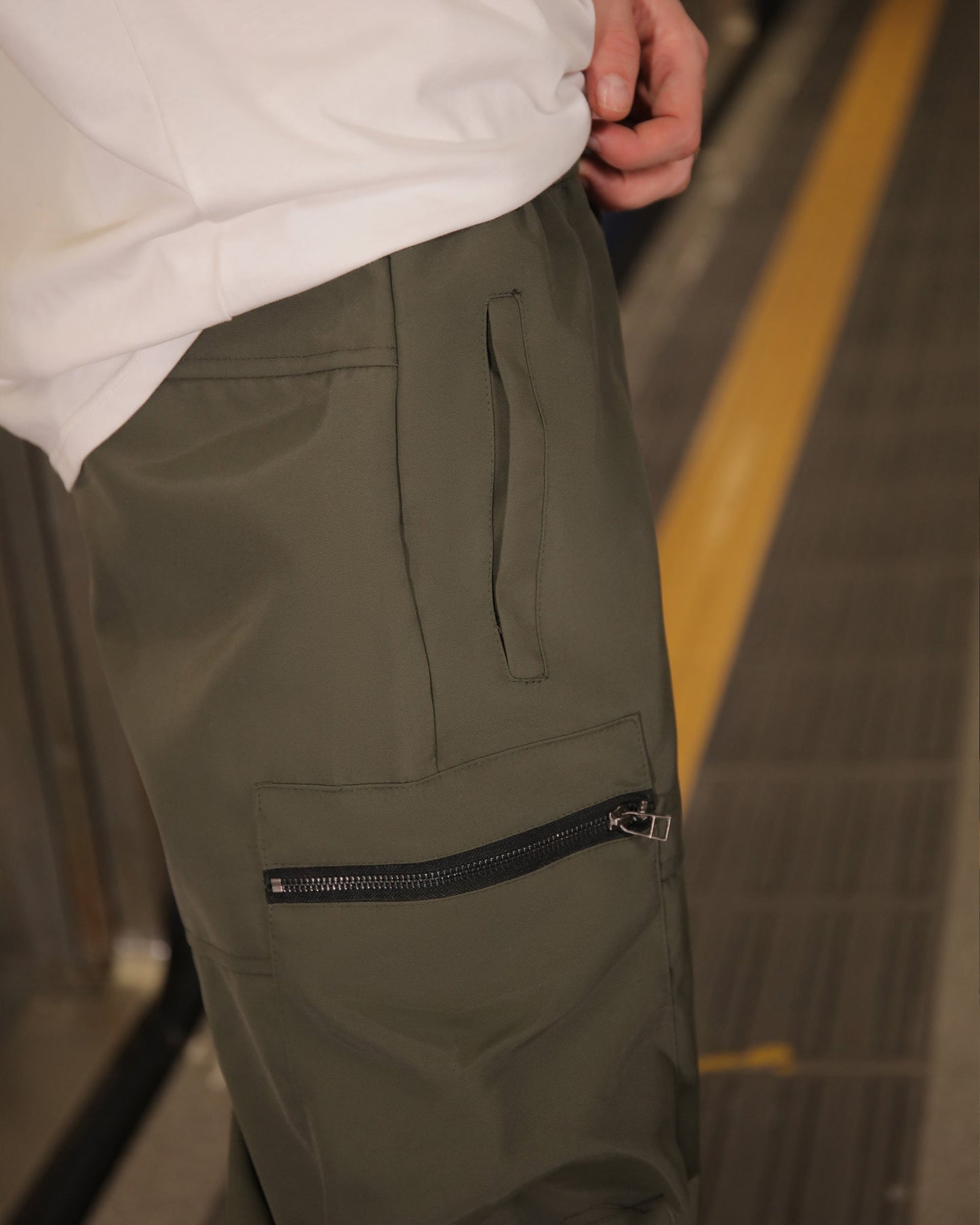 Close-up of Logeqi stylish cargo pants for men in olive green with zippered pocket detail