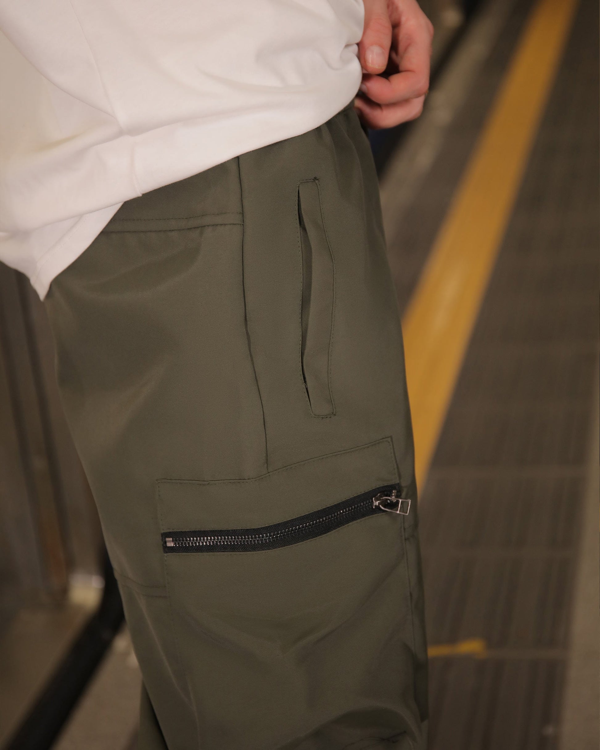 Close-up of Logeqi stylish cargo pants for men in olive green with zippered pocket detail