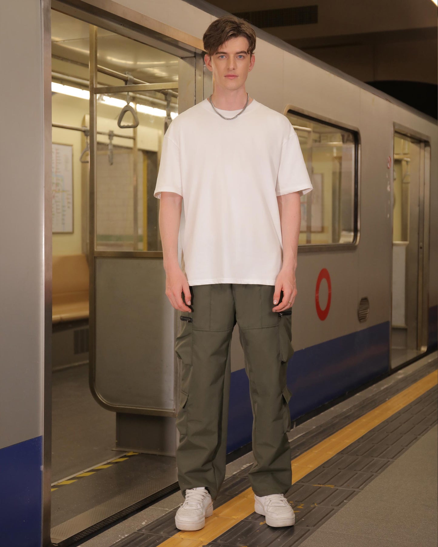 Logeqi stylish cargo pants for men in olive green worn by a male model standing on a subway platform