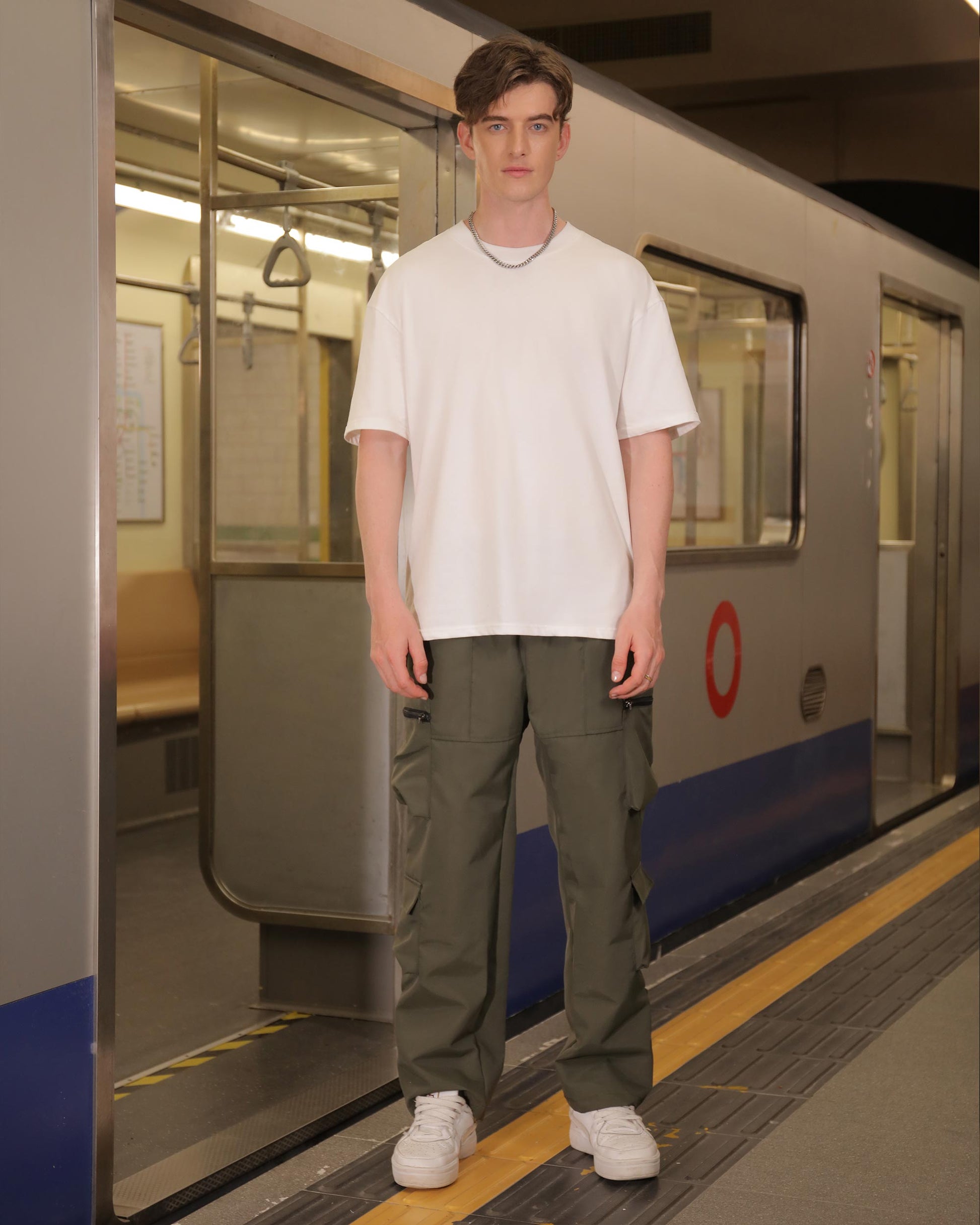 Logeqi stylish cargo pants for men in olive green worn by a male model standing on a subway platform