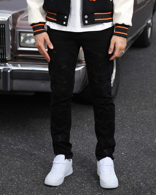 Logeqi black straight leg jeans worn with white sneakers and a varsity jacket on street