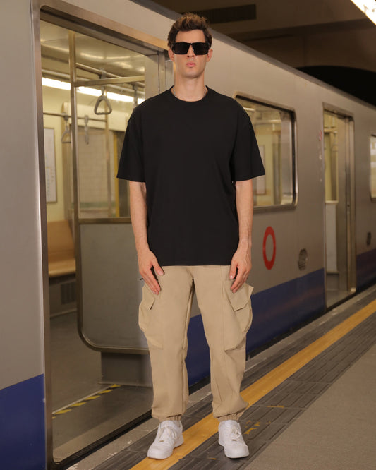 Logeqi versatile cargo pants in beige worn by a man with black t-shirt and white sneakers at subway station