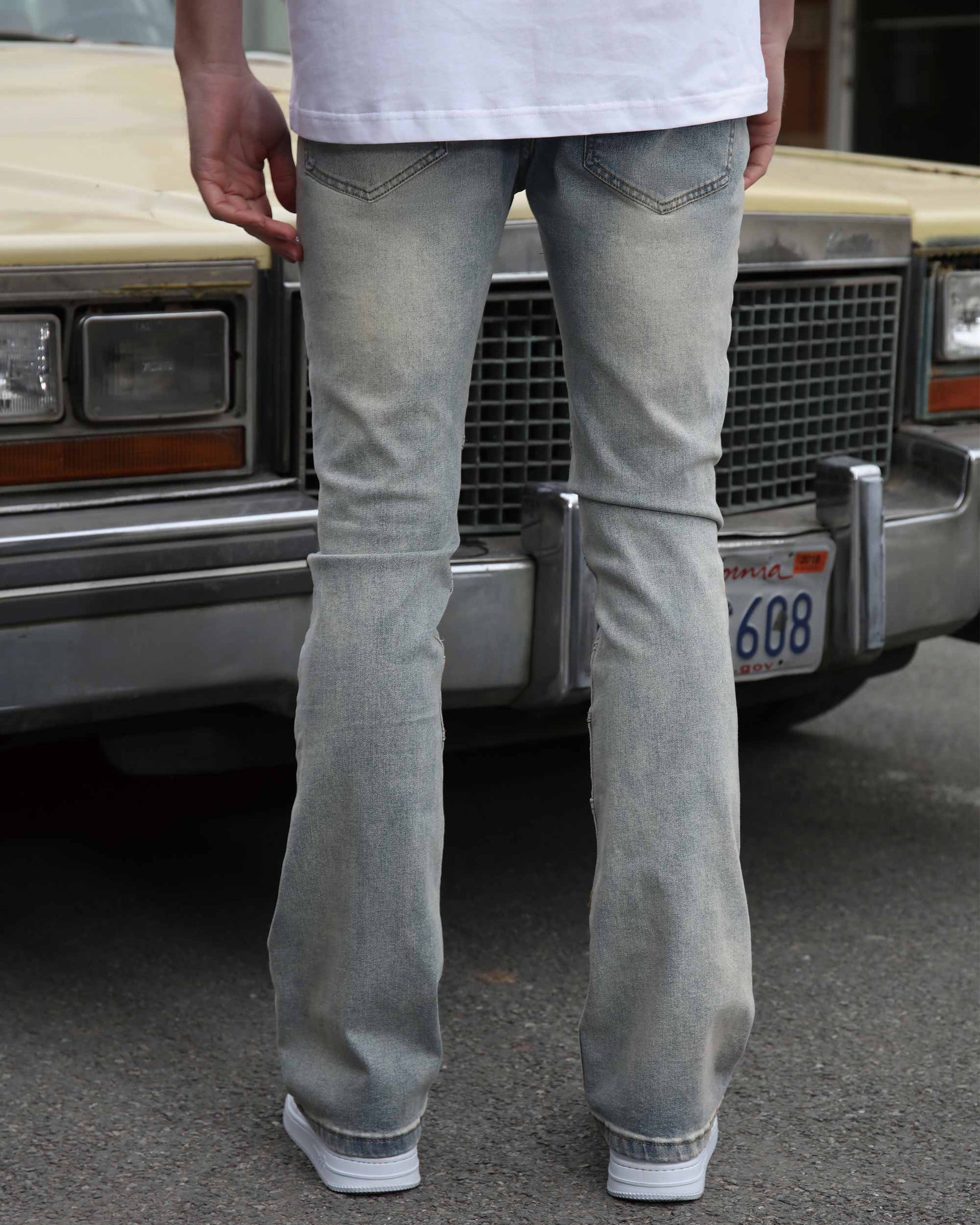 Logeqi vintage distressed blue jeans shown from the back worn by a person standing in front of a classic car