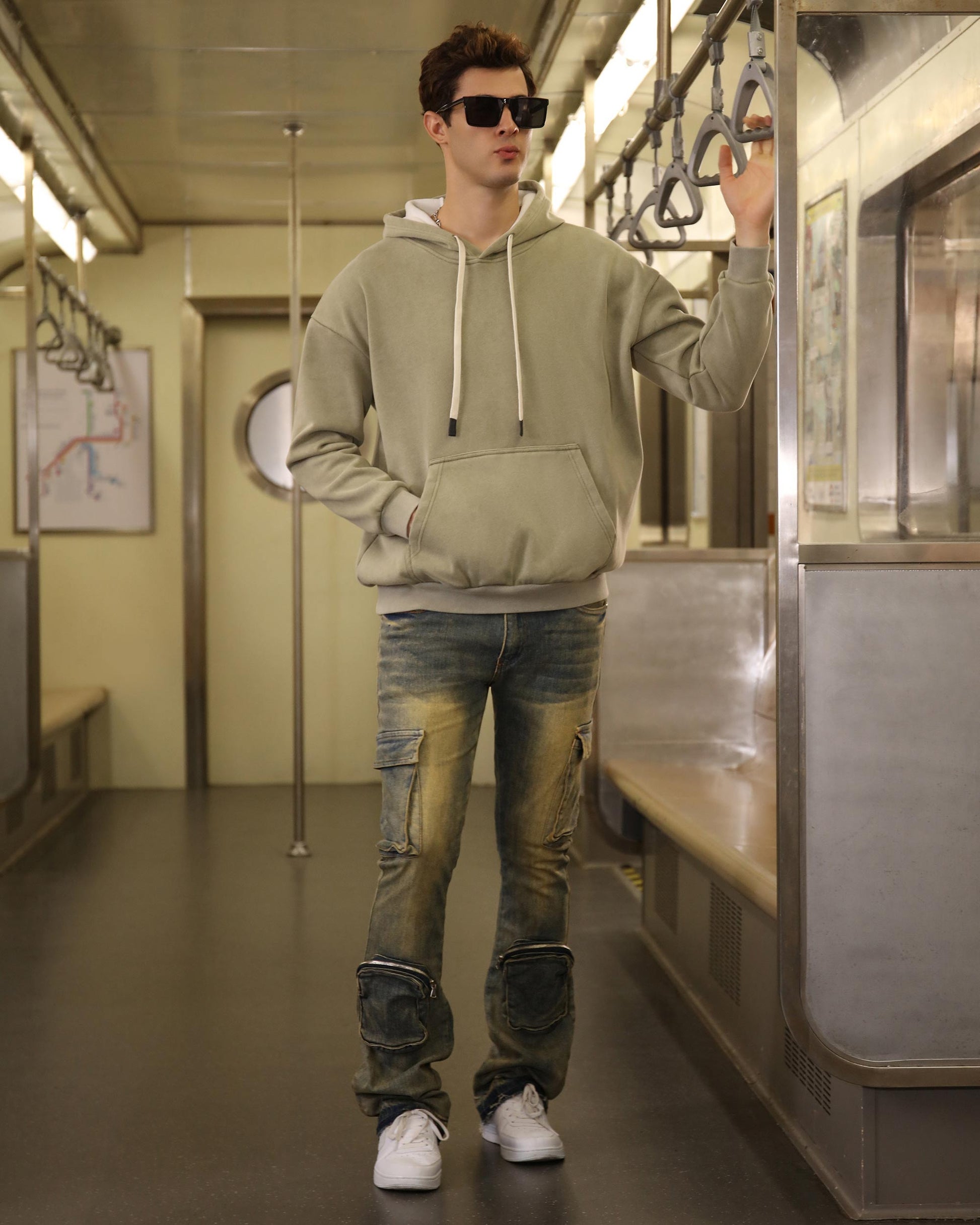 Logeqi vintage distressed cargo jeans styled with a green hoodie and white sneakers in a subway setting