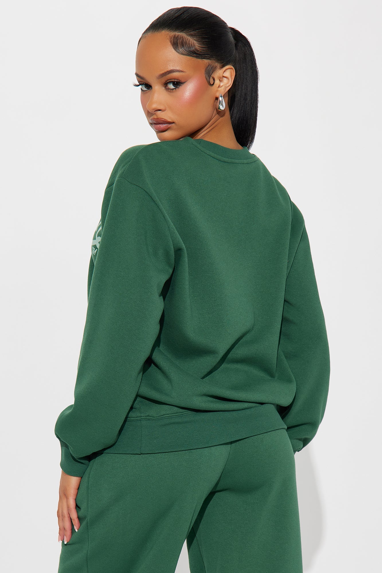 Model wearing a green Von Dutch distressed crewneck sweatshirt styled with matching bottoms