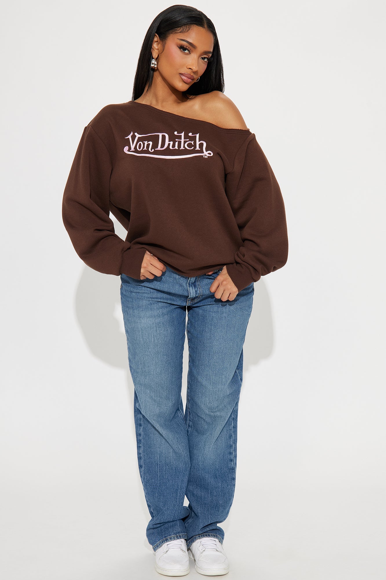 Von Dutch off shoulder sweatshirt in brown paired with blue jeans for a stylish casual look