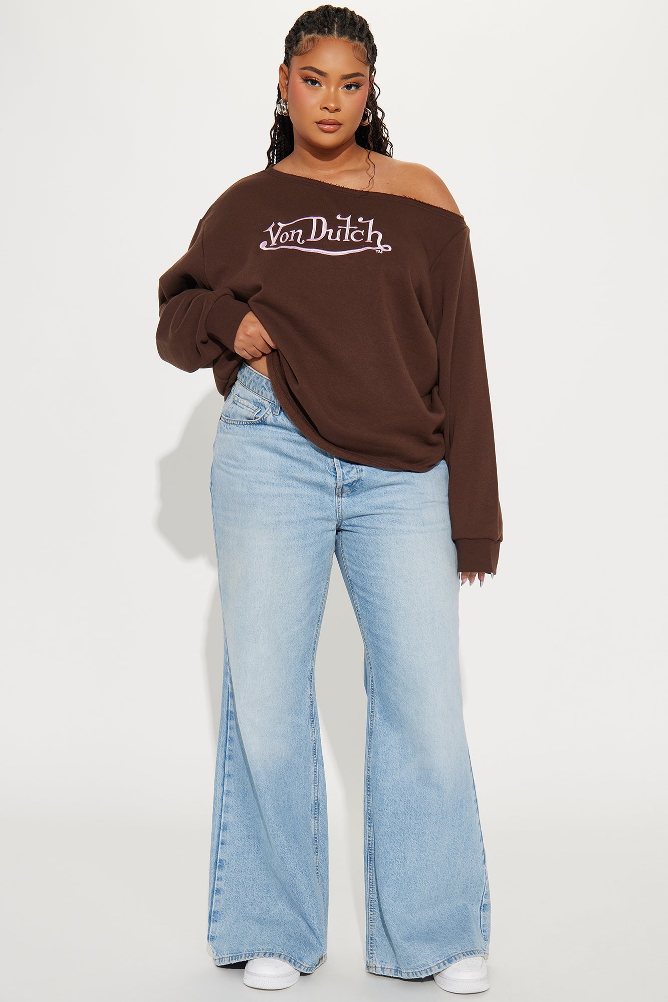 Woman wearing a Von Dutch off shoulder sweatshirt paired with light blue wide-leg jeans