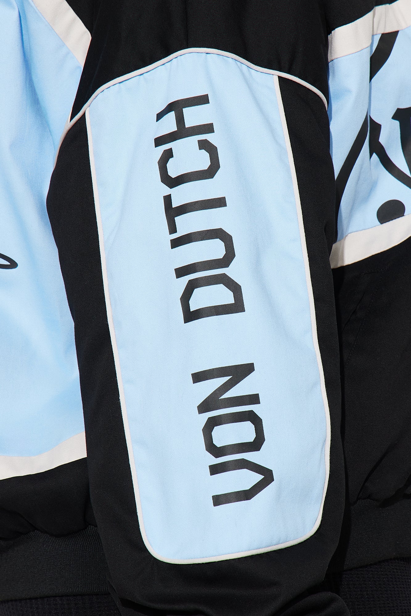 Close-up of Von Dutch moto jacket featuring bold logo detailing in light blue and black fabric