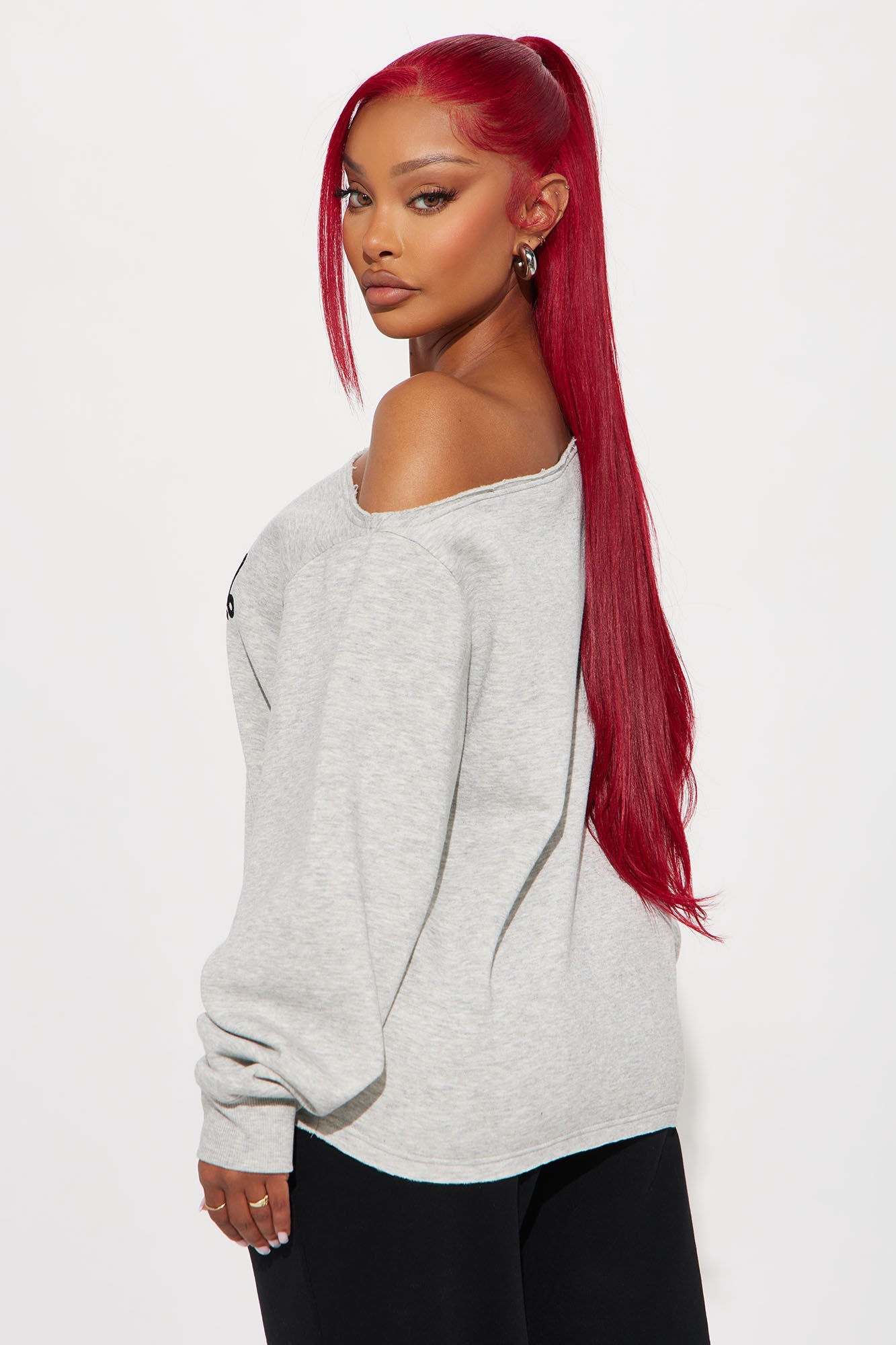 Model wearing a gray Von Dutch off shoulder sweatshirt, styled with long red hair and chic accessories