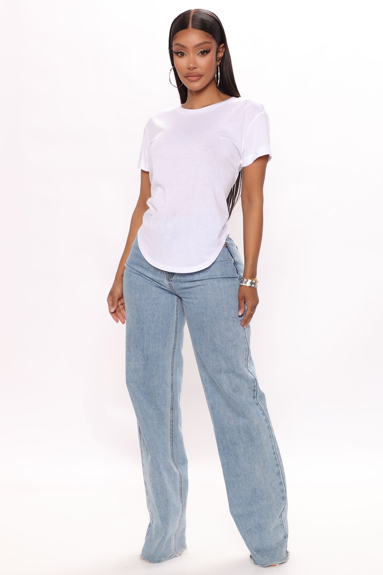 Fashion Nova model wearing a casual white cuffed sleeve top paired with light blue jeans