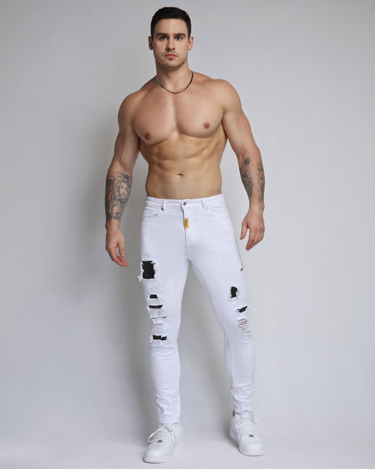 Stylish white ripped jeans with diamond patch modeled by a muscular man in a casual pose